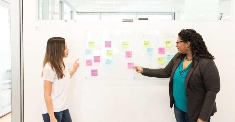 Zwei Personen besprechen Haftnotizen an einer Glaswand im Büro