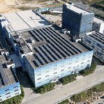 Luftaufnahme eines Industrie- oder Rechenzentrumsstandorts mit großflächigen Solaranlagen auf den Dächern als Symbol für GreenOps, Cloud-Nachhaltigkeit und CO2-Reporting