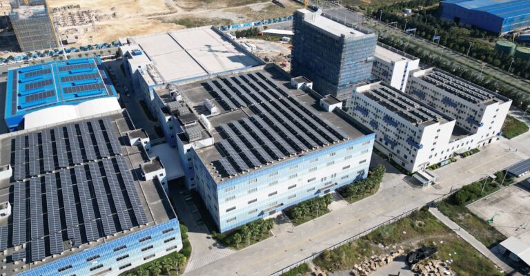 Luftaufnahme eines Industrie- oder Rechenzentrumsstandorts mit großflächigen Solaranlagen auf den Dächern als Symbol für GreenOps, Cloud-Nachhaltigkeit und CO2-Reporting