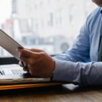 Mitarbeiter prüft Unterlagen auf Klemmbrett als Symbol für ISO IEC 20000 1 Auditnachweise