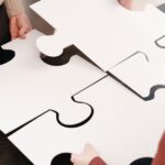 Mehrere Personen setzen große weiße Puzzleteile zusammen und symbolisieren die Integration mehrerer Service-Provider im SIAM-Betrieb