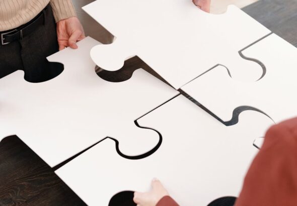 Mehrere Personen setzen große weiße Puzzleteile zusammen und symbolisieren die Integration mehrerer Service-Provider im SIAM-Betrieb
