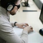 Blinder Mann mit Braille-Unterlagen und Computer im Büro als Symbol für barrierefreie digitale Serviceportale