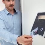 Mann nutzt Zugangskarte an Kartenleser im Büro als Symbol für kontrollierten Zugriff