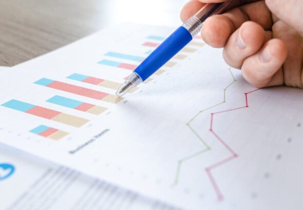 Hand mit Stift über Diagrammen als Symbol für SaaS-Auswertung und Ausstiegsplanung