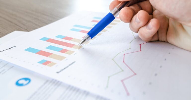 Hand mit Stift über Diagrammen als Symbol für SaaS-Auswertung und Ausstiegsplanung