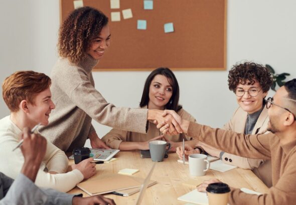 Menschen an einem Besprechungstisch als Symbol für zentrale Rollen- und Rechtepflege in GitHub Enterprise Teams