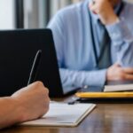 Person notiert eine Freigabe in einem Gespräch als Symbol für nachvollziehbare Änderungsnachweise im IT-Betrieb