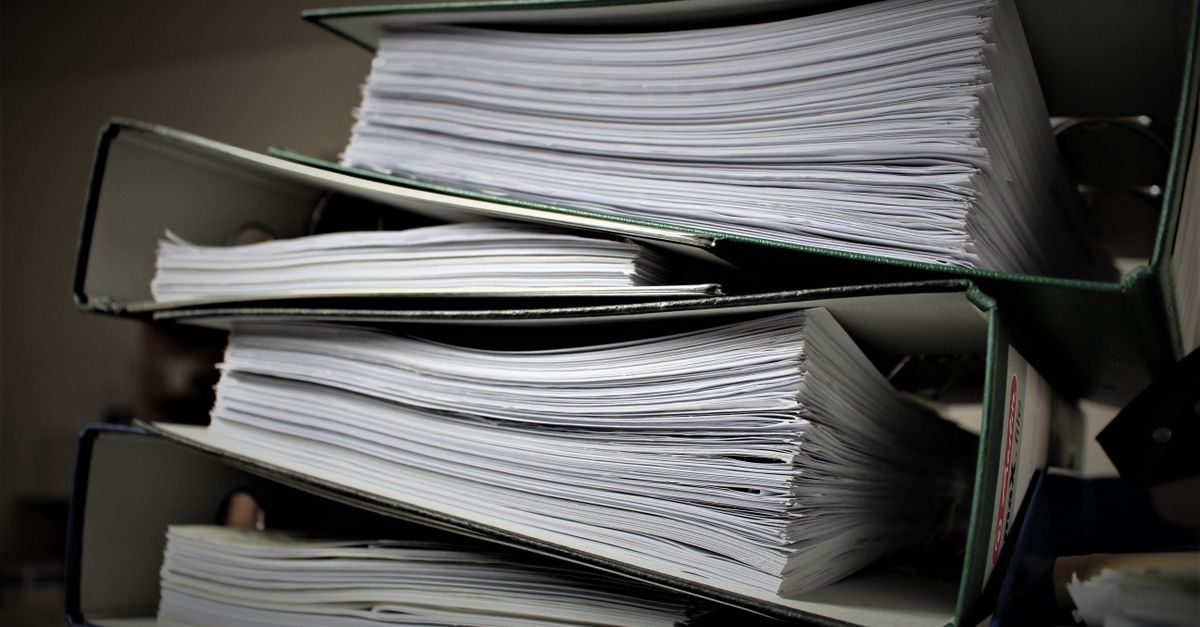 Aktenordner und Papierstapel als Symbol für alte IT-Dienste, Nachweise und geordneten Rückbau