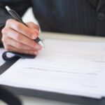 Person unterschreibt Unterlagen als Symbol für Ausnahmefreigabe, Ablaufdatum und Audit-Nachweis