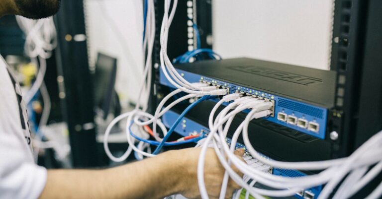 Techniker arbeitet an Netzwerkkabeln im Schrank als Symbol für DNS, Erreichbarkeit und Betriebsverantwortung