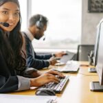 Service Desk Mitarbeiterin mit Headset prüft eine Kundenantwort am Bildschirm als Symbol für menschliche Kontrolle von KI-Vorschlägen