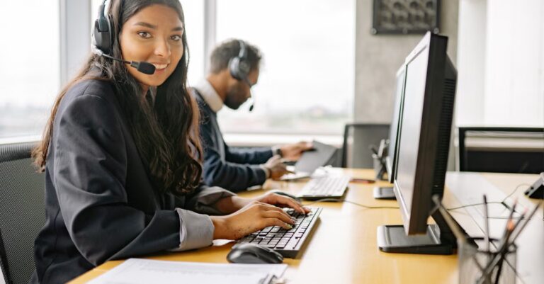 Service Desk Mitarbeiterin mit Headset prüft eine Kundenantwort am Bildschirm als Symbol für menschliche Kontrolle von KI-Vorschlägen