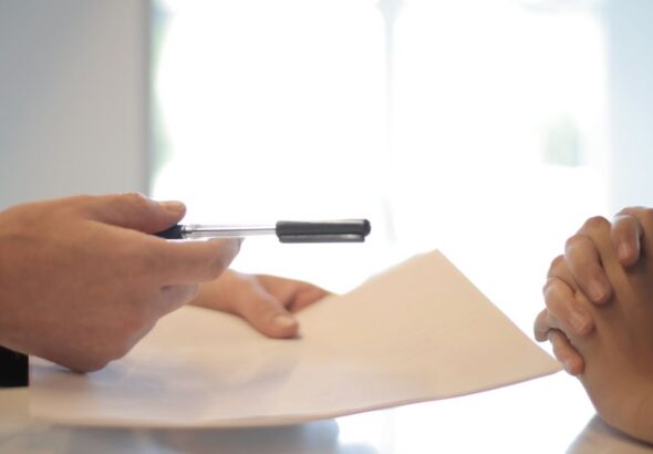 Dokumentenprüfung mit Stift als Motiv für Änderungsfreigabe und Rückweg im IT-Betrieb
