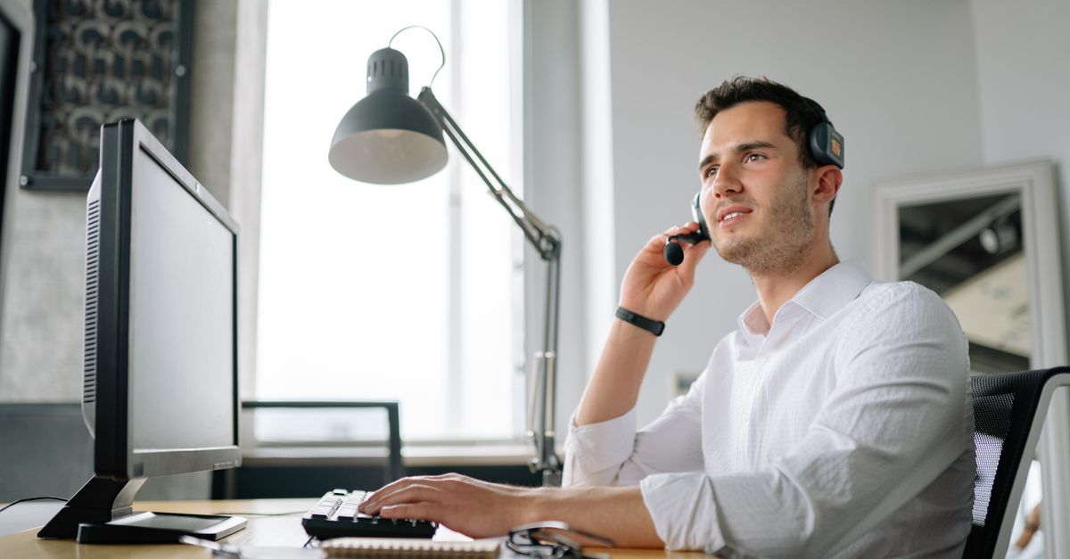 Service-Desk-Mitarbeiter mit Headset am Bildschirm für Serviceportal und Servicekatalog