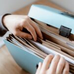 Hände durchsuchen geordnete Papierablage als Symbol für Servicekatalog-Anfragen, Pflichtfelder und fehlende Angaben im Service Desk