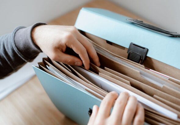 Hände durchsuchen geordnete Papierablage als Symbol für Servicekatalog-Anfragen, Pflichtfelder und fehlende Angaben im Service Desk