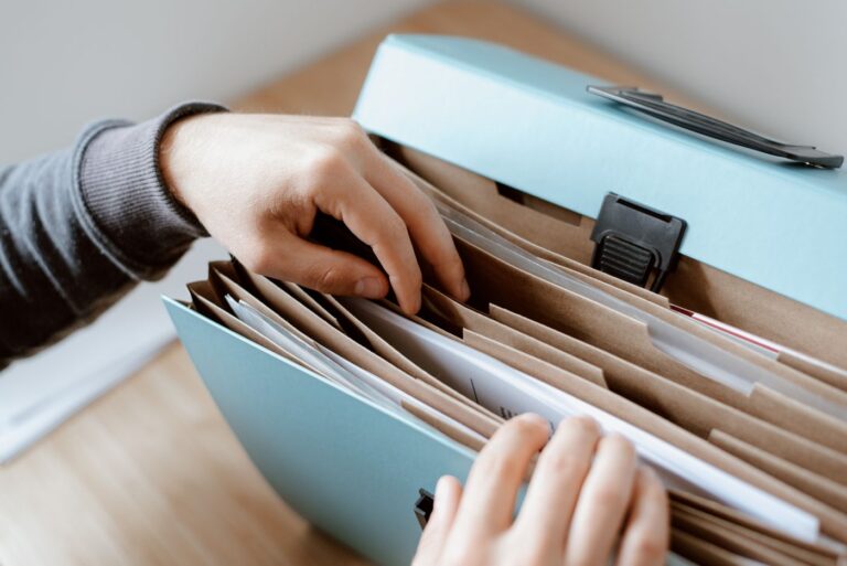 Hände durchsuchen geordnete Papierablage als Symbol für Servicekatalog-Anfragen, Pflichtfelder und fehlende Angaben im Service Desk