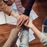 Team legt Hände über Unterlagen als Symbol für geprüfte Notfall-Runbooks, Rollen und Eskalation im IT-Betrieb