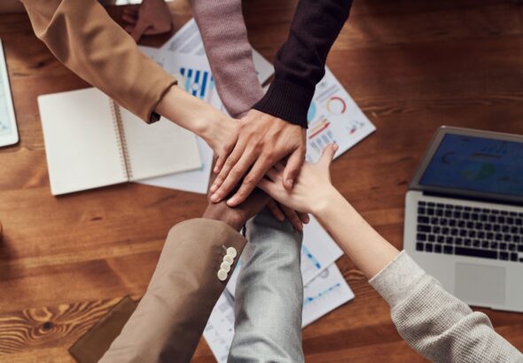 Team legt Hände über Unterlagen als Symbol für geprüfte Notfall-Runbooks, Rollen und Eskalation im IT-Betrieb
